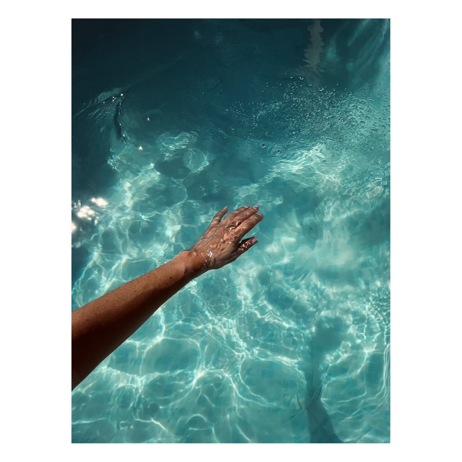 Fine Art lifestyle photograph of hand in turquoise pool light by Andrea Polmüller